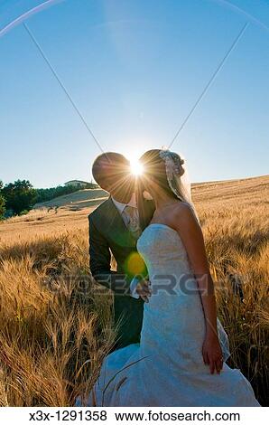 Stock Photo - Newlyweds kissing at sunset in Umbria, Italy. Fotosearch