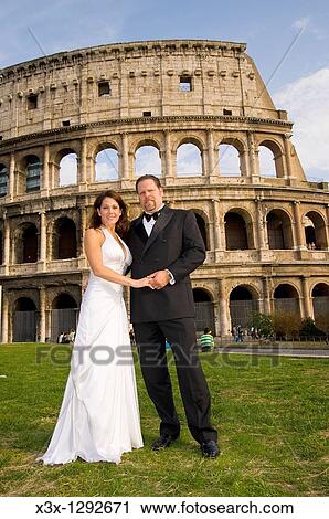Newlyweds standing in front of the Roman Colosseum in Rome Italy View Large Photo Image Stock Image - Newlyweds standing in front of the Roman Colosseum in Rome Italy. Fotosearch