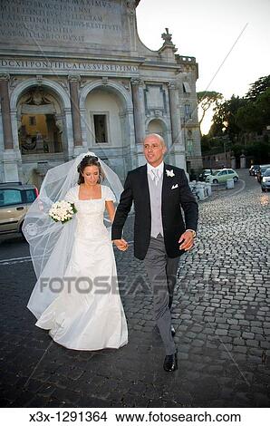 Newlyweds walking across a Sanpietrini road Fontanone dell Acqua Paola known as the Fontanone del Gianicolo Rome, Italy View Large Photo Image Picture - Newlyweds walking across a Sanpietrini road Fontanone dell Acqua Paola known as the Fontanone del Gianicolo Rome, Italy. Fotosearch
