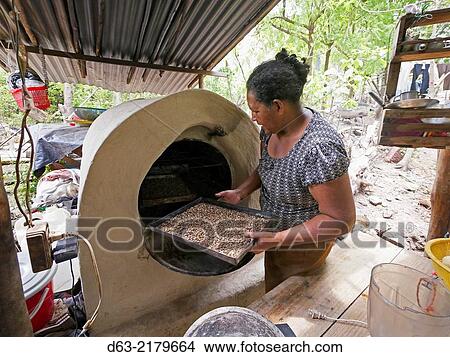 Nicaragua. FEDICAMP projects. Family of Maria Ramos Olivas (54) and her son Deixin Cruz Ramos (25) in the community of Riito. Maria using her wood fired ooven to dry coffee. View Large Photo Image Picture - Nicaragua. FEDICAMP projects. Family of Maria Ramos Olivas (54) and her son Deixin Cruz Ramos (25) in the community of Riito. Maria using her wood fired ooven to dry coffee.. Fotosearch