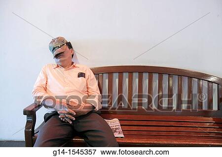 Stock Photo - Nicaragua, Managua, Avenida Simon Bolivar, Plaza Inter, shopping mall, bench, public area, Hispanic, man, resting, sleeping, face covered, cap, napping,. Fotosearch