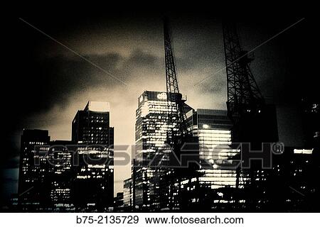 Stock Photo - Night view of office buildings and cranes in The Docks, Canary Wharf, London, England, UK, Europe. Fotosearch