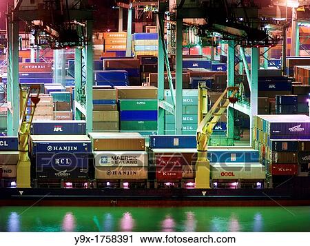 Stock Image - Night view of the Port of Singapore Authority PSA in Singapore PSA Singapore Terminals is the world largest container transhipment hub, handling about one-fifth of the world's total container transhipment throughput. Fotosearch
