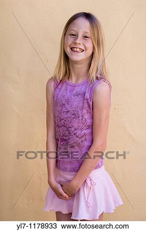 Nine-year-old blonde girl in a pink top and purple skirt sticking her tongue between her teeth and laughing View Large Photo Image Stock Image - Nine-year-old blonde girl in a pink top and purple skirt sticking her tongue between her teeth and laughing. Fotosearch