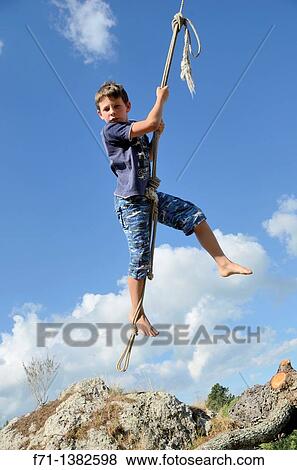 Stock Photo - Nine year old boy launching from a tree on a rope swing Atiamuri, New Zealand. Fotosearch