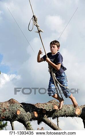 Stock Photography - Nine year old boy launching from a tree on a rope swing Atiamuri, New Zealand. Fotosearch
