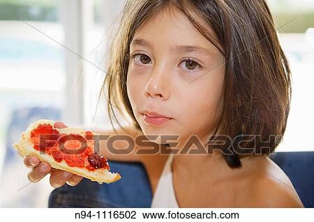 Stock Image - Nine year old, newly awakened, have breakfast toast with strawberry jam, looking at the camera.. Fotosearch