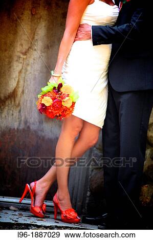 Stock Photo - non-traditional bride & groom embracing in front of the rustic winery @ their wedding wearing orange shoes. Fotosearch