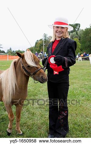 Stock Photo - North America, Canada, Ontario, girl with minature pony and first place ribbon at agricultural fair. Fotosearch