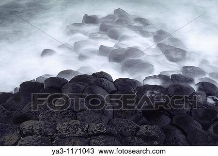 Stock Image - NORTHERN IRELAND, County Antrim, Giants Causeway Waves crash against the hexagonal basalts rock formations of this world heritage site. Fotosearch