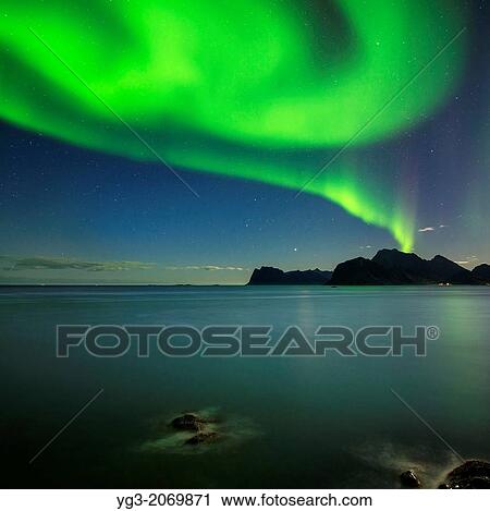 Northern Lights shine in sky over sea and mountains of Vestvagoy, from near Myrland, Lofoten Islands, Norway. View Large Photo Image Stock Image - Northern Lights shine in sky over sea and mountains of Vestvagoy, from near Myrland, Lofoten Islands, Norway.. Fotosearch