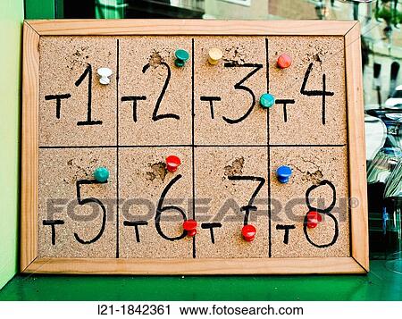 Stock Image - Numbers written on a wooden plank. Each number represents a table in a restaurant. Waiters nailed in every issue orders.. Fotosearch