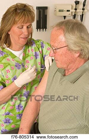 Nurse, giving shot or injection to elder man, in medical office View Large Photo Image Picture - Nurse, giving shot or injection to elder man, in medical office. Fotosearch