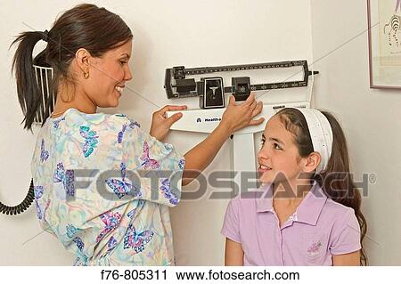 Stock Image - Nurse, measuring height of young girl. Fotosearch