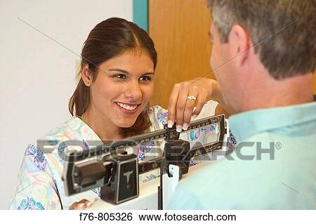 Nurse, weighing male patient, in medical office View Large Photo Image Stock Photograph - Nurse, weighing male patient, in medical office. Fotosearch