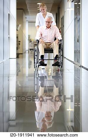 Stock Image - Nurse with patient in wheelchair, Corridor, Onkologikoa Hospital, Oncology Institute, Case Center for prevention, diagnosis and treatment of cancer, Donostia, San Sebastian, Gipuzkoa, Basque Country, Spain. Fotosearch