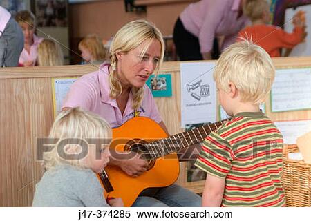 Nursrey school teacher, playing a guitar to a small group of children (3-4 year olds) View Large Photo Image Stock Photography - Nursrey school teacher, playing a guitar to a small group of children (3-4 year olds). Fotosearch