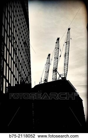 Stock Image - Office building in the foreground and another building under construction with three cranes. London, England, UK, Europe.. Fotosearch