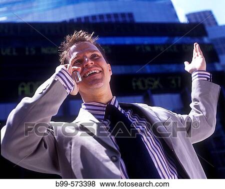 Stock Photo - Office worker with telephone, Below stock market ticker display.. Fotosearch