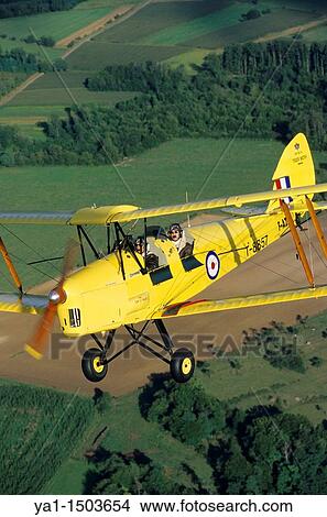 Old British trainer biplane De Havilland DH-82a Tiger Moth in flight over France View Large Photo Image Picture - Old British trainer biplane De Havilland DH-82a Tiger Moth in flight over France. Fotosearch