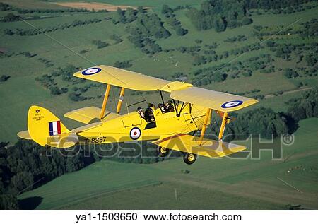 Old British trainer biplane De Havilland DH-82a Tiger Moth in flight over France View Large Photo Image Stock Image - Old British trainer biplane De Havilland DH-82a Tiger Moth in flight over France. Fotosearch