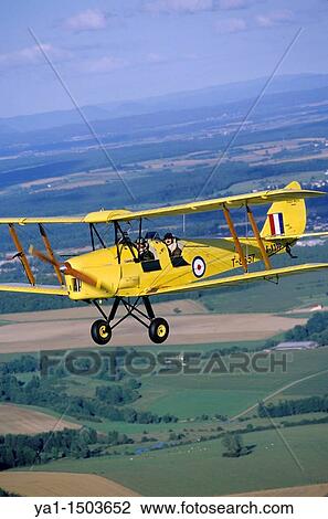 Stock Image - Old British trainer biplane De Havilland DH-82a Tiger Moth in flight over France. Fotosearch