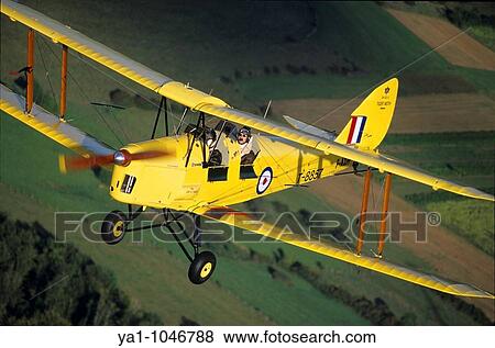 Old British trainer biplane De Havilland DH-82a Tiger Moth in flight over France View Large Photo Image Stock Photo - Old British trainer biplane De Havilland DH-82a Tiger Moth in flight over France. Fotosearch