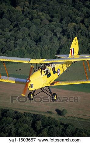 Old British trainer biplane De Havilland DH-82a Tiger Moth in flight over France View Large Photo Image Stock Photo - Old British trainer biplane De Havilland DH-82a Tiger Moth in flight over France. Fotosearch