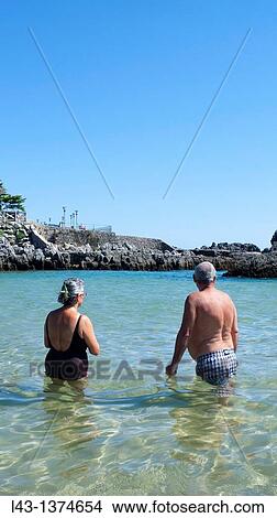 Picture - Old couple having a bath in the beach of Isla, province of cantabria, spain. Fotosearch