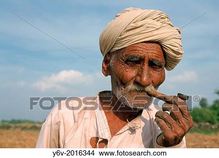 Picture - Old farmer smoking a pipe. Gujarat state, India. He belongs to the Rebari caste.. Fotosearch