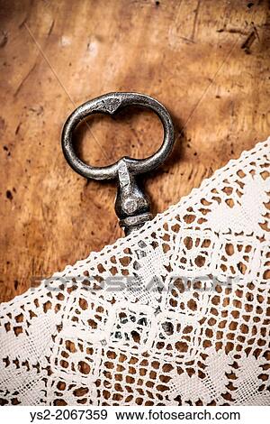 Old fashioned key lying on vintage wooden table hidden under lace tablecloth. View Large Photo Image Stock Photo - Old fashioned key lying on vintage wooden table hidden under lace tablecloth.. Fotosearch