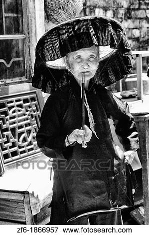 Old Hakka woman with pipe in the old walled city of Kam Tin in the New Territories area of Hong Kong This is a dying breed of woman for tourists with black hats and black clothes with smoking View Large Photo Image Stock Photo - Old Hakka woman with pipe in the old walled city of Kam Tin in the New Territories area of Hong Kong This is a dying breed of woman for tourists with black hats and black clothes with smoking. Fotosearch