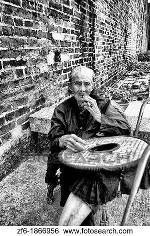 Old Hakka woman with pipe in the old walled city of Kam Tin in the New Territories area of Hong Kong This is a dying breed of woman for tourists with black hats and black clothes with smoking View Large Photo Image Stock Photograph - Old Hakka woman with pipe in the old walled city of Kam Tin in the New Territories area of Hong Kong This is a dying breed of woman for tourists with black hats and black clothes with smoking. Fotosearch
