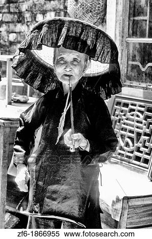 Old Hakka woman with pipe in the old walled city of Kam Tin in the New Territories area of Hong Kong This is a dying breed of woman for tourists with black hats and black clothes with smoking View Large Photo Image Stock Photography - Old Hakka woman with pipe in the old walled city of Kam Tin in the New Territories area of Hong Kong This is a dying breed of woman for tourists with black hats and black clothes with smoking. Fotosearch