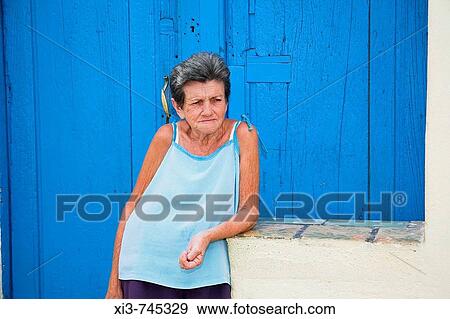 Stock Photo - Old lady leaning on a wall and standing in front of her house, Trinidad, Sancti Spiritus Province, Cuba. Fotosearch