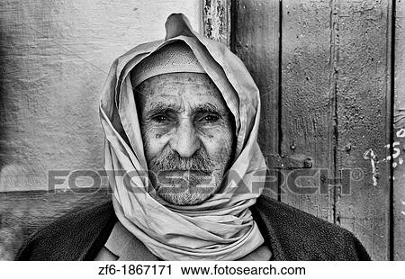 Stock Image - Old local colorful Arab portait of local man in Douz in Sahara Desert of Tunisia Africa. Fotosearch
