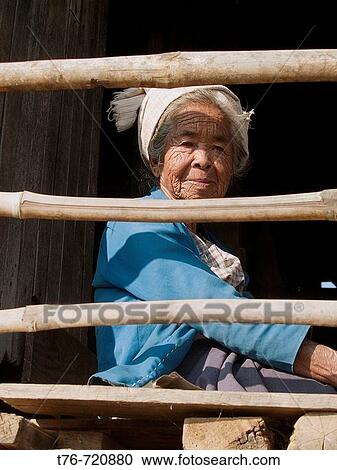 Stock Image - Old Pa O woman sitting on her balcony at Inle Lake in Myanmar. Fotosearch