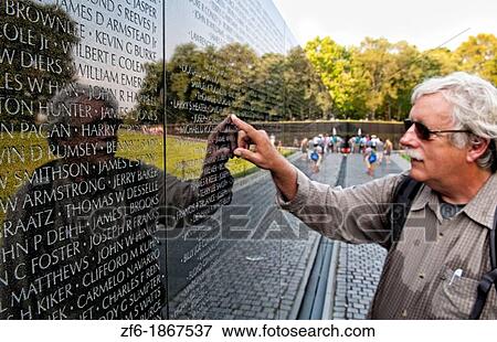 Old soldier looking at friends name at reflections of hero names of war dead at Vietnam Veterans Memorial Wall monument in Washington DC USA View Large Photo Image Stock Photo - Old soldier looking at friends name at reflections of hero names of war dead at Vietnam Veterans Memorial Wall monument in Washington DC USA. Fotosearch