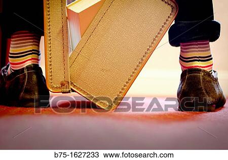 Old suitcase open with books in, between the legs of a man with striped socks View Large Photo Image Stock Image - Old suitcase open with books in, between the legs of a man with striped socks. Fotosearch