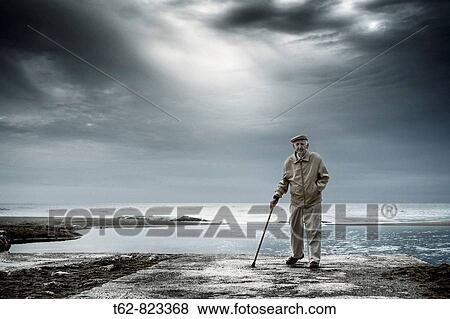 Stock Photo - Old taking a walk by the beach after the storm. Fotosearch