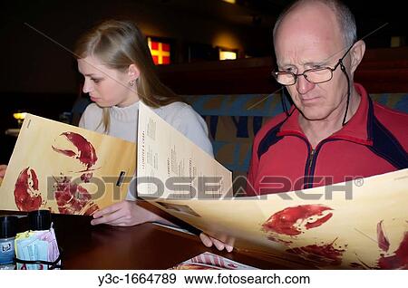 Older man and young woman reading menu at a seafood restaurant View Large Photo Image Stock Photo - Older man and young woman reading menu at a seafood restaurant. Fotosearch