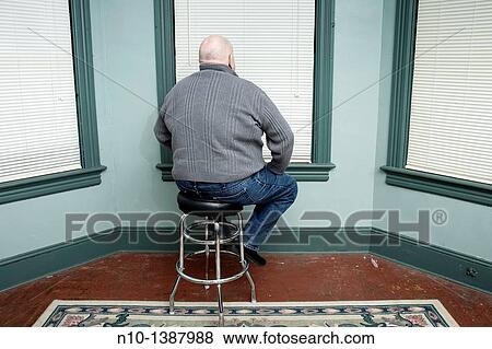 Older man sitting on a stool, facing a window View Large Photo Image Stock Photo - Older man sitting on a stool, facing a window. Fotosearch