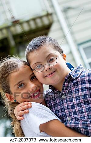 Older sister hugging and lifting younger brother with Down syndrome. View Large Photo Image Stock Image - Older sister hugging and lifting younger brother with Down syndrome.. Fotosearch