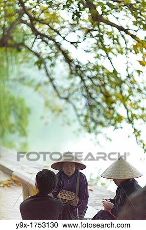 Older woman wearing traditional Non La conical hats at the Hoan Kiem Lake in Vietnam View Large Photo Image Stock Image - Older woman wearing traditional Non La conical hats at the Hoan Kiem Lake in Vietnam. Fotosearch