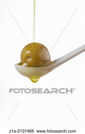 Stock Photograph - Olive oil pouring into an olive on a white background.. Fotosearch