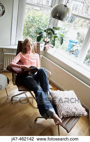 On a chair reading by the window View Large Photo Image Stock Image - On a chair reading by the window. Fotosearch