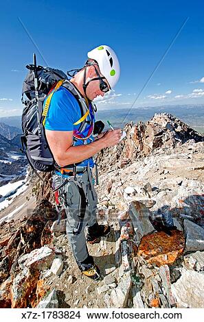Picture - on the summit signing the register after climbing The June Couloir on the North Face of Williams Peak high above the Sawtooth Valley in the Sawtooth Mountains near the town of Stanley in central Idaho. Fotosearch
