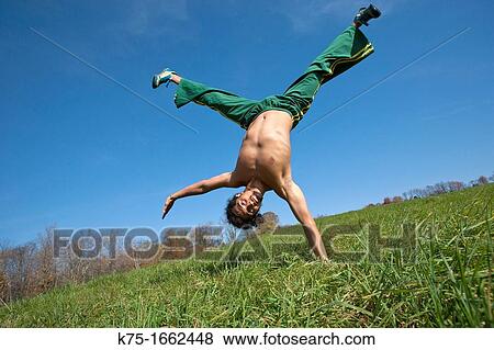 Stock Photo - One arm handstand in field. Fotosearch