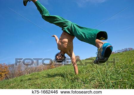 Stock Photograph - One arm handstand in field. Fotosearch