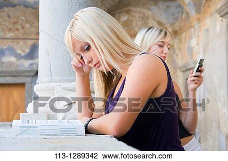 One girl is studying another is talking on the cellular phone View Large Photo Image Stock Image - One girl is studying another is talking on the cellular phone. Fotosearch